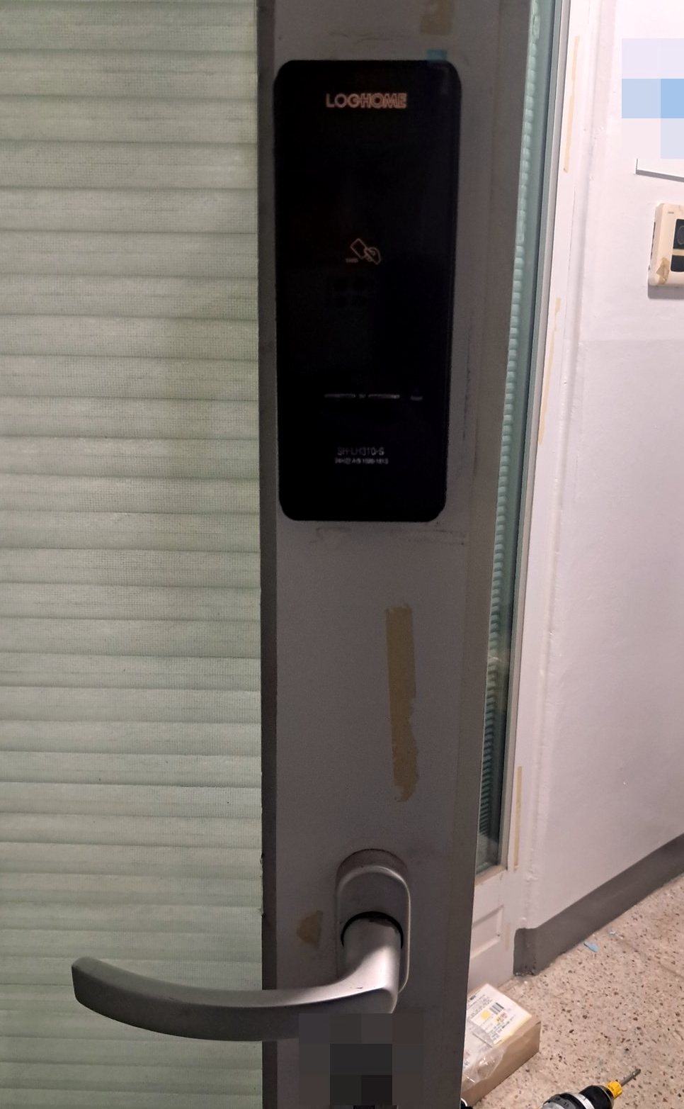 시흥시 신현동 출장 — 은회색 샷시 문에 단 앞면이 흐릿한 검은 도어락과 아래 은빛 레버 손잡이